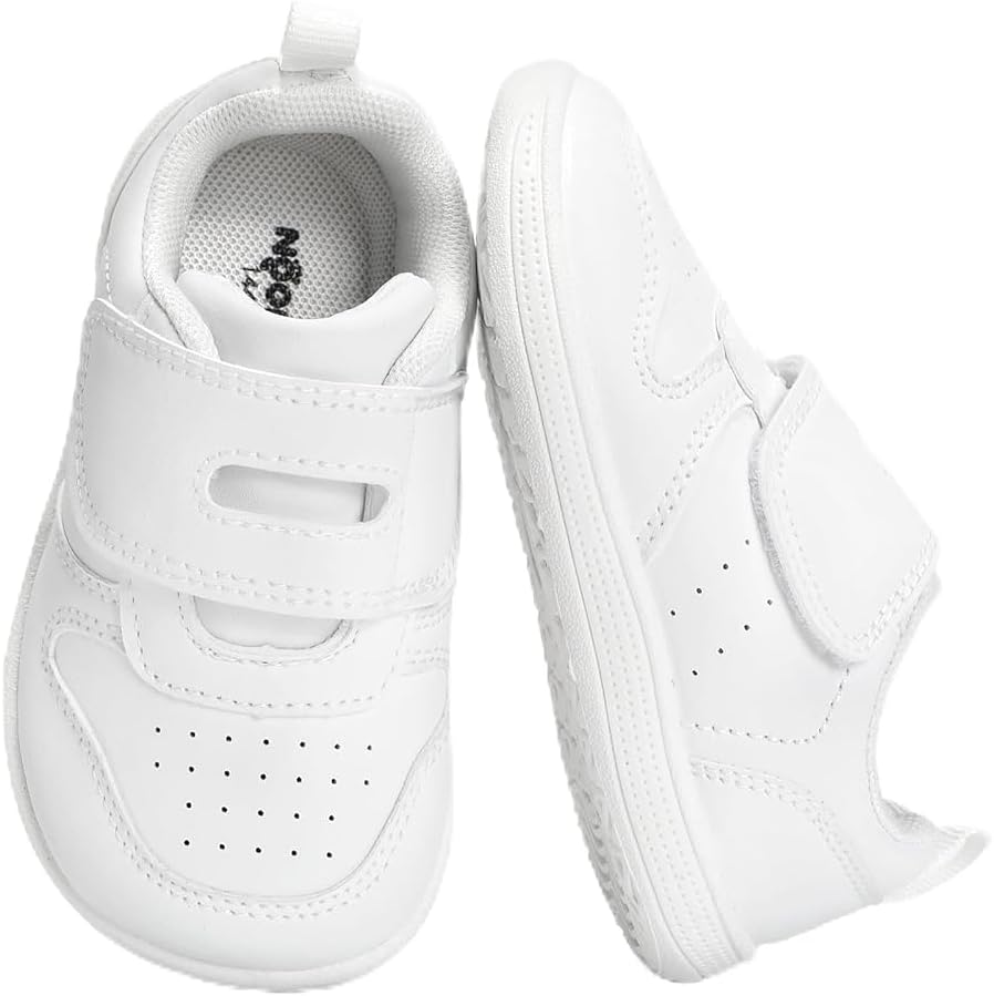 Installing Pavo Wide Toe Box Walking Shoes for Toddlers Boys Girls on a wooden floor with a toddler's hand holding the Velcro strap